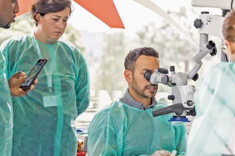 doctor looking into microscope with person behind him