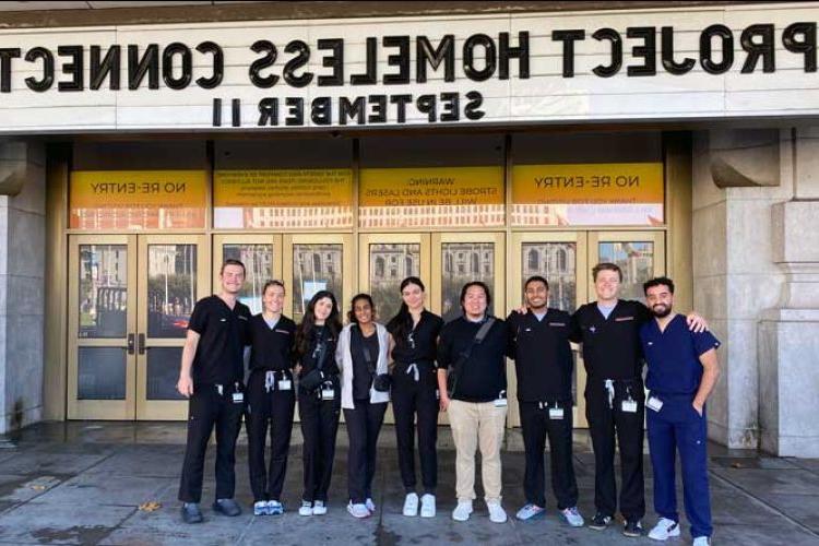 Group of student volunteers in front of Bill Graham Civic Auditorium under a marquee reading Project 首页less Connect 82