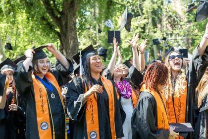 student-athletes throw their graduation caps into the air at commencement